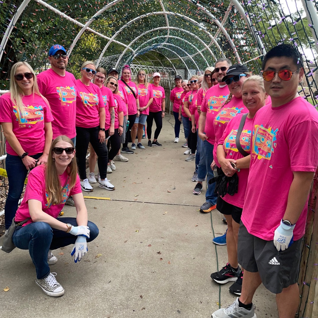 Nancy Perry Day of Caring in their hot pink shirts pose for a photo while working on the Zoo Lights tunnel